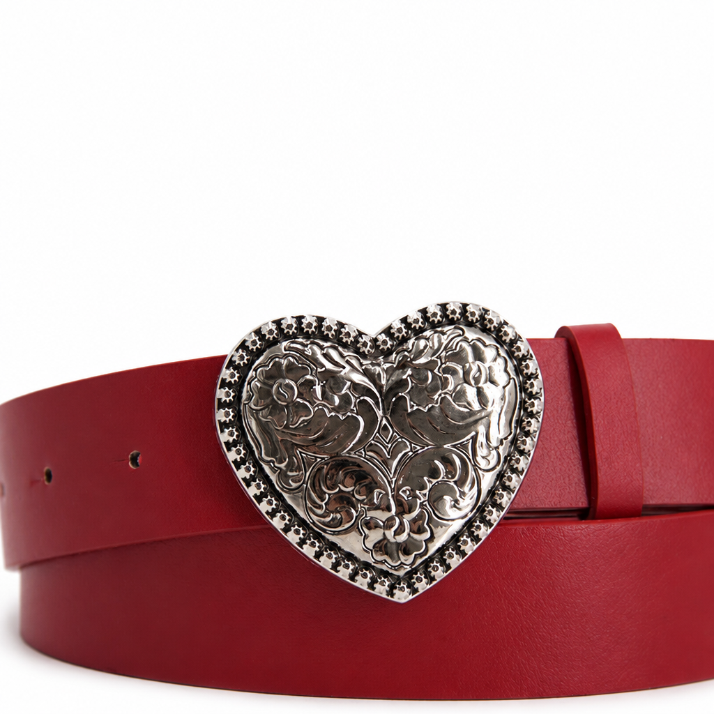 Detalle de hebilla plateada en forma de corazón del cinturón rojo sobre fondo blanco